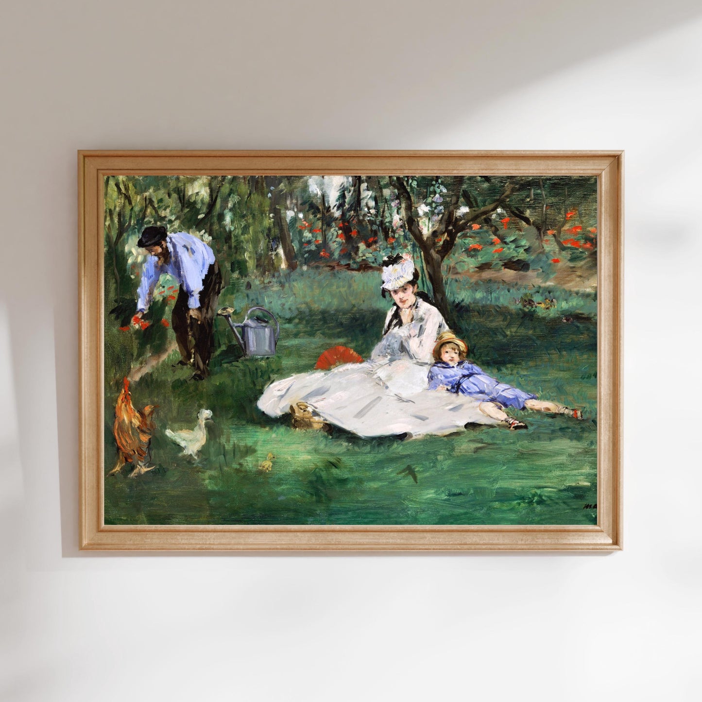 The image is a framed painting depicting a woman sitting on a blanket in a grassy field, with a man and a child standing nearby.