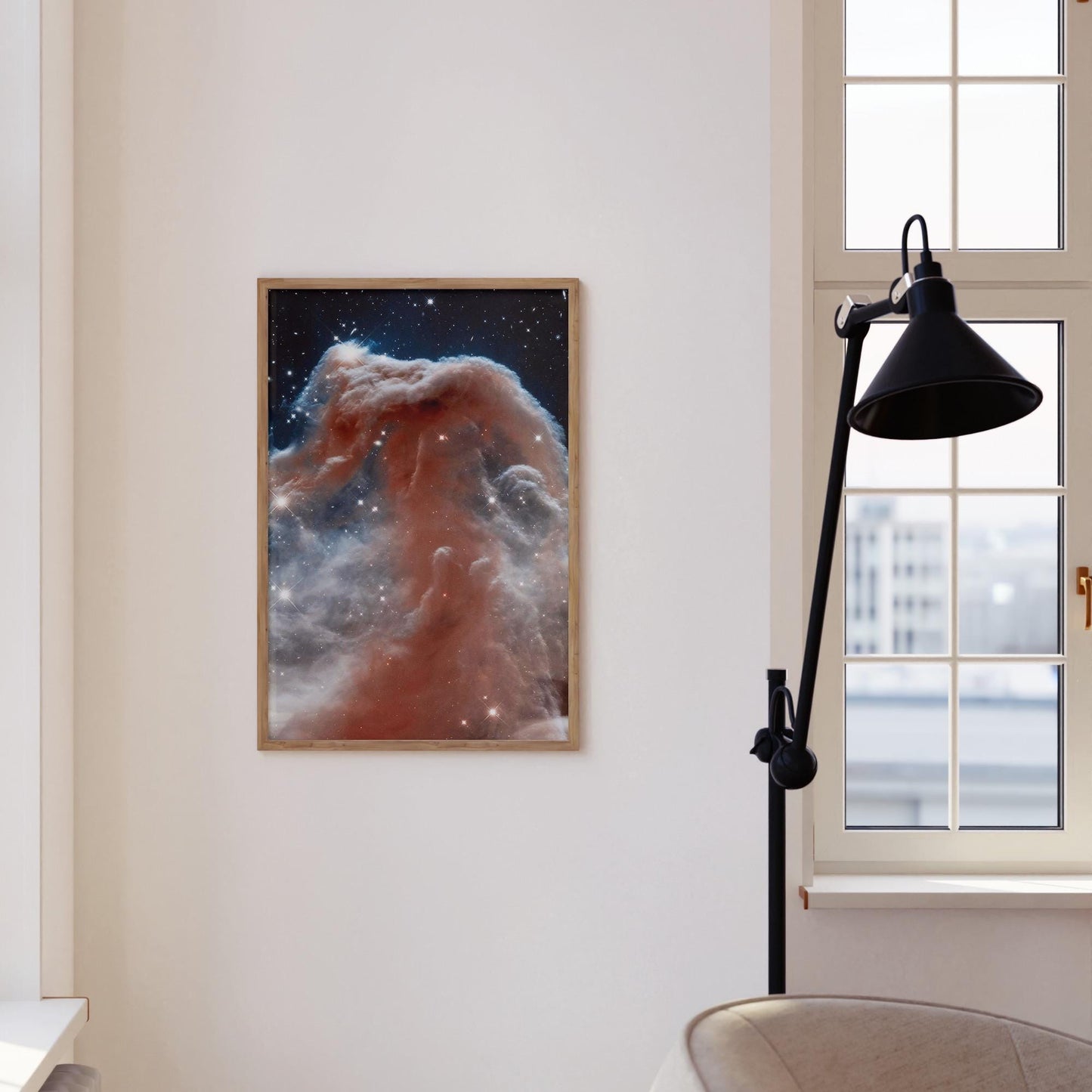 a framed photograph of a nebula, a large cloud of dust and gas in space, hanging on a white wall.