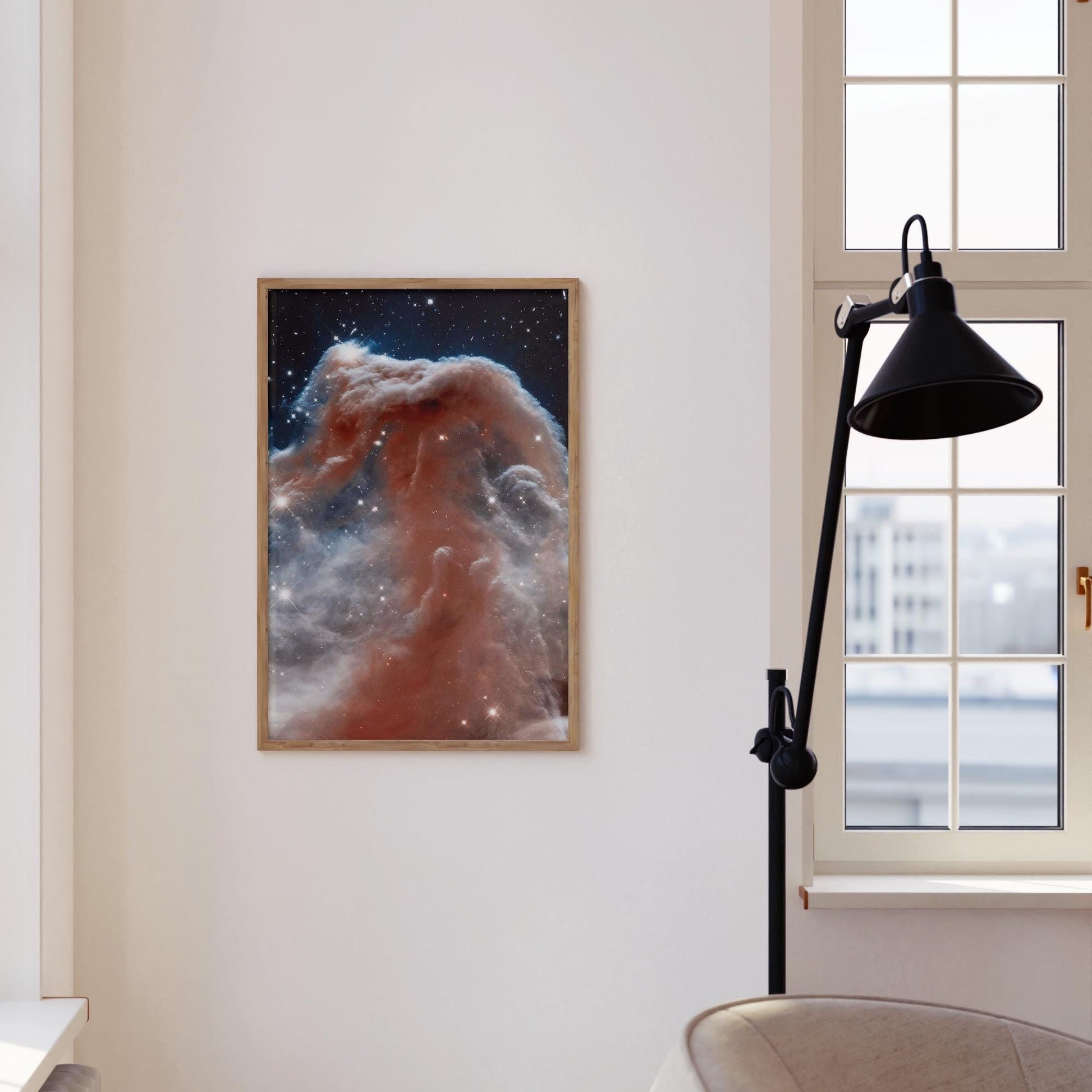 a framed photograph of a nebula, a large cloud of dust and gas in space, hanging on a white wall.