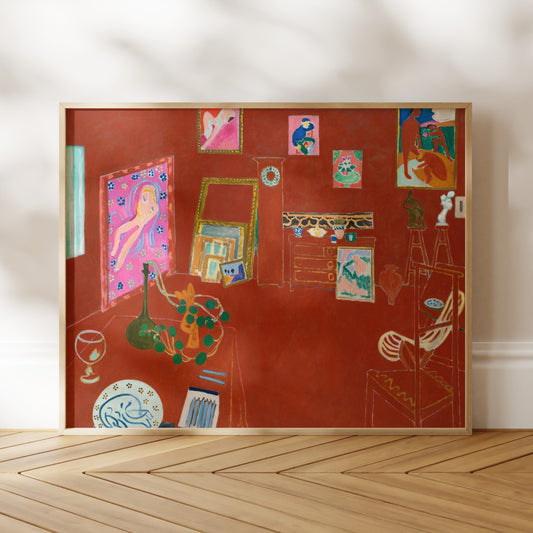 The image is a framed painting depicting a room with various objects, including a vase, a chair, and a table. The painting has a vibrant color palette and is displayed on a wooden floor against a white wall.