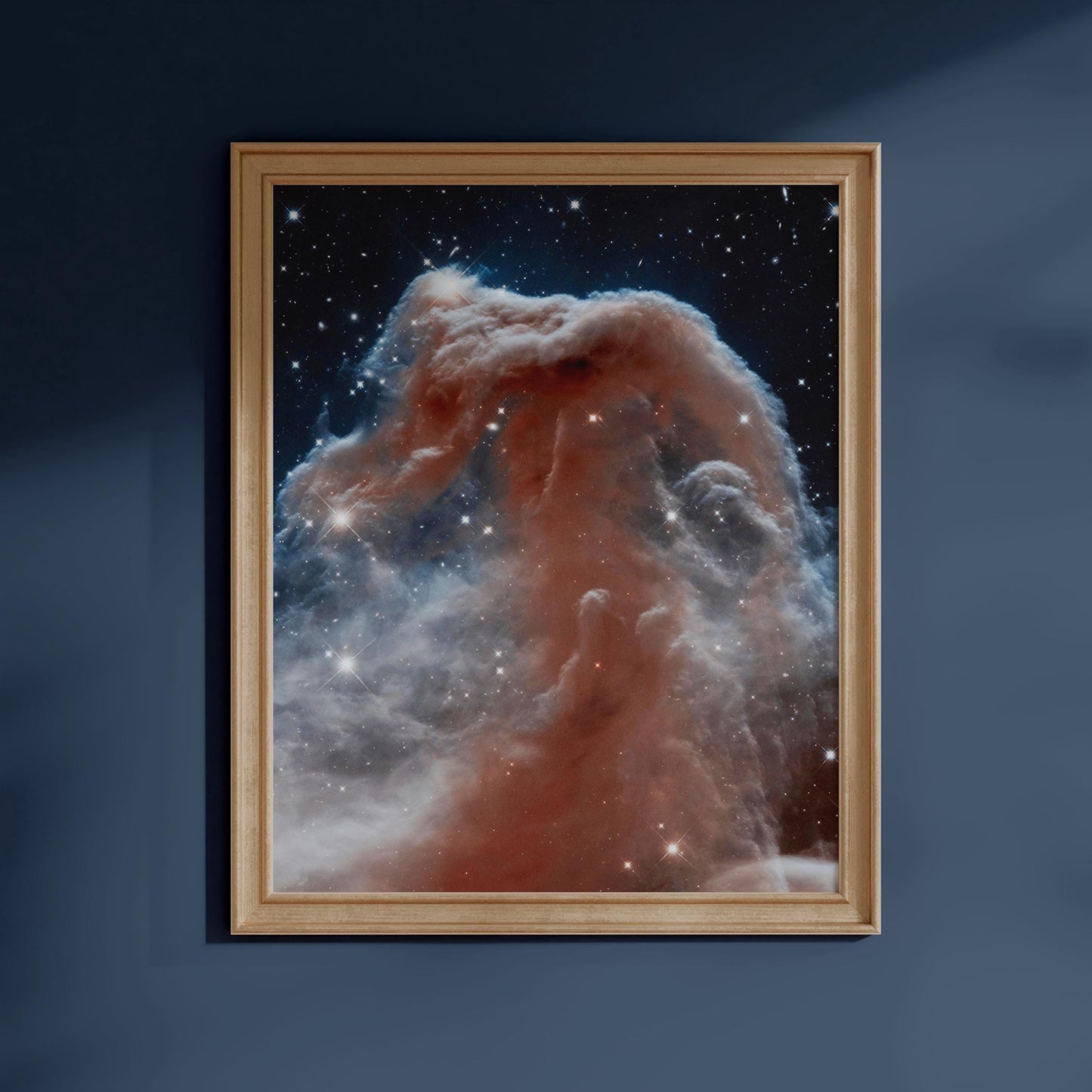 The image is a framed photograph of a nebula, a vast cloud of gas and dust in space, against a dark blue background.