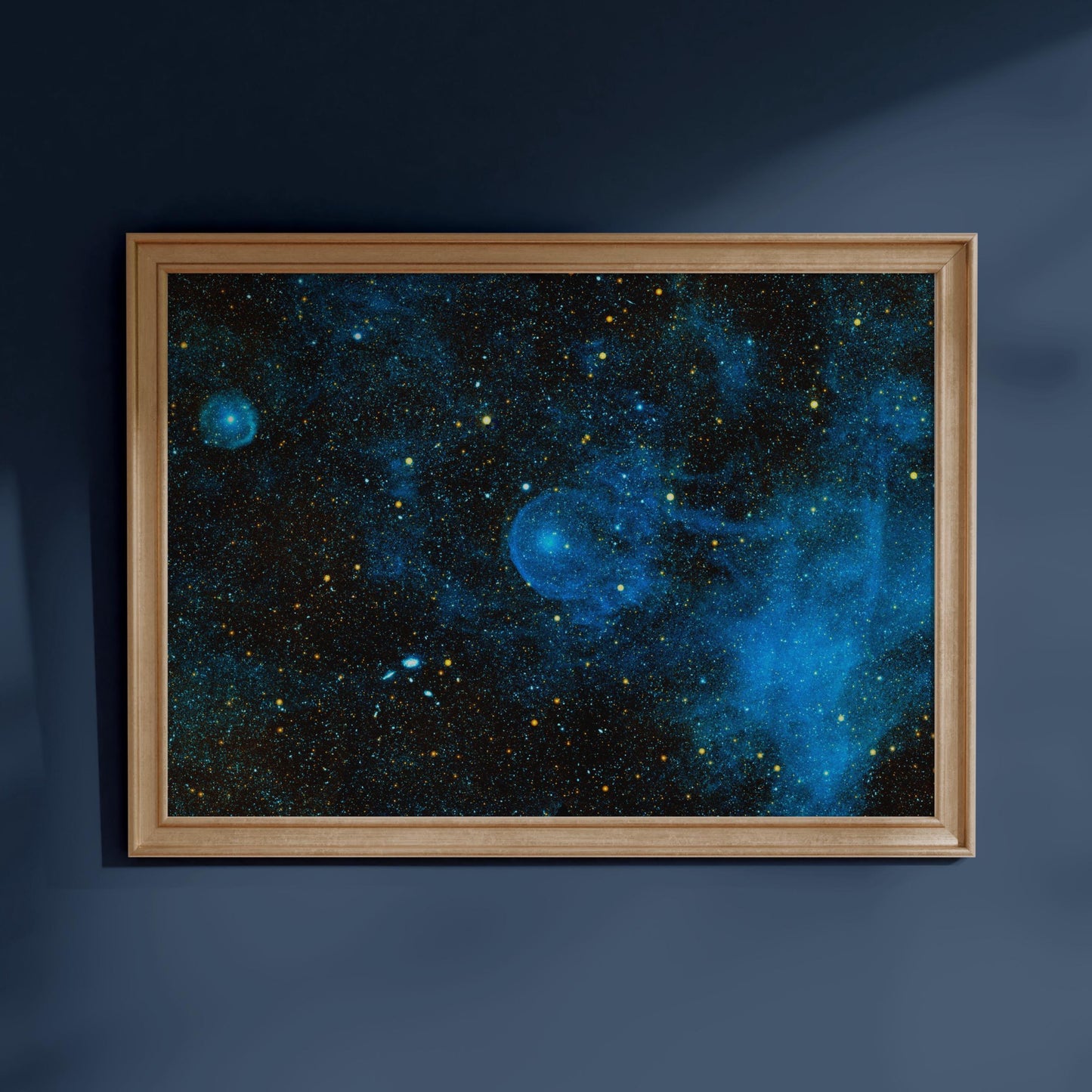 The image is a framed picture of a starry night sky, hanging on a blue wall.