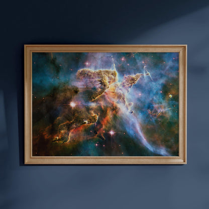 The image is a framed painting of a colorful nebula, a vast cloud of gas and dust in space, with vibrant hues of orange, yellow, and blue.