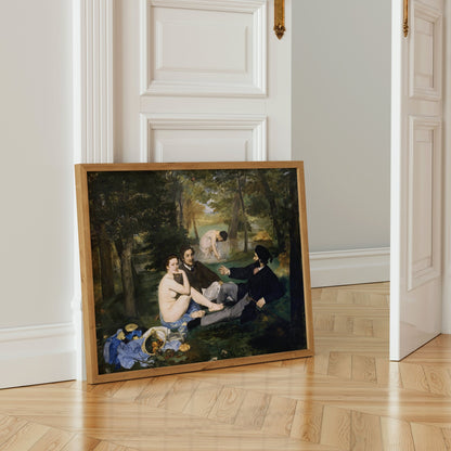 The image is a framed painting depicting a group of people sitting on the grass in a park, with trees in the background.