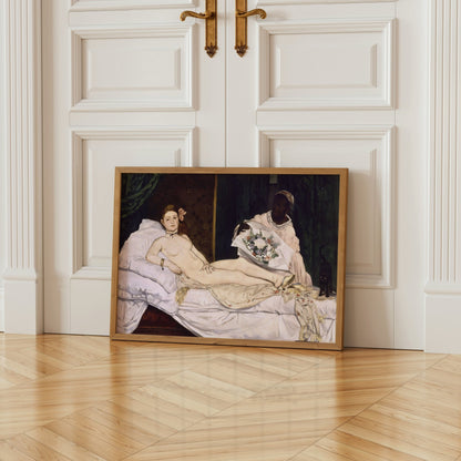 The image is a framed painting depicting a nude woman lying on a bed, with a woman holding a bouquet of flowers next to her.