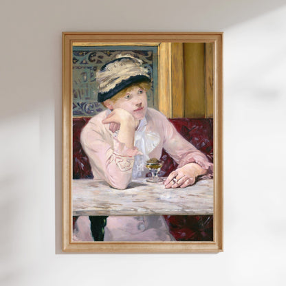 A framed painting depicting a woman in a pink dress and hat, sitting at a table and holding a glass of wine.
