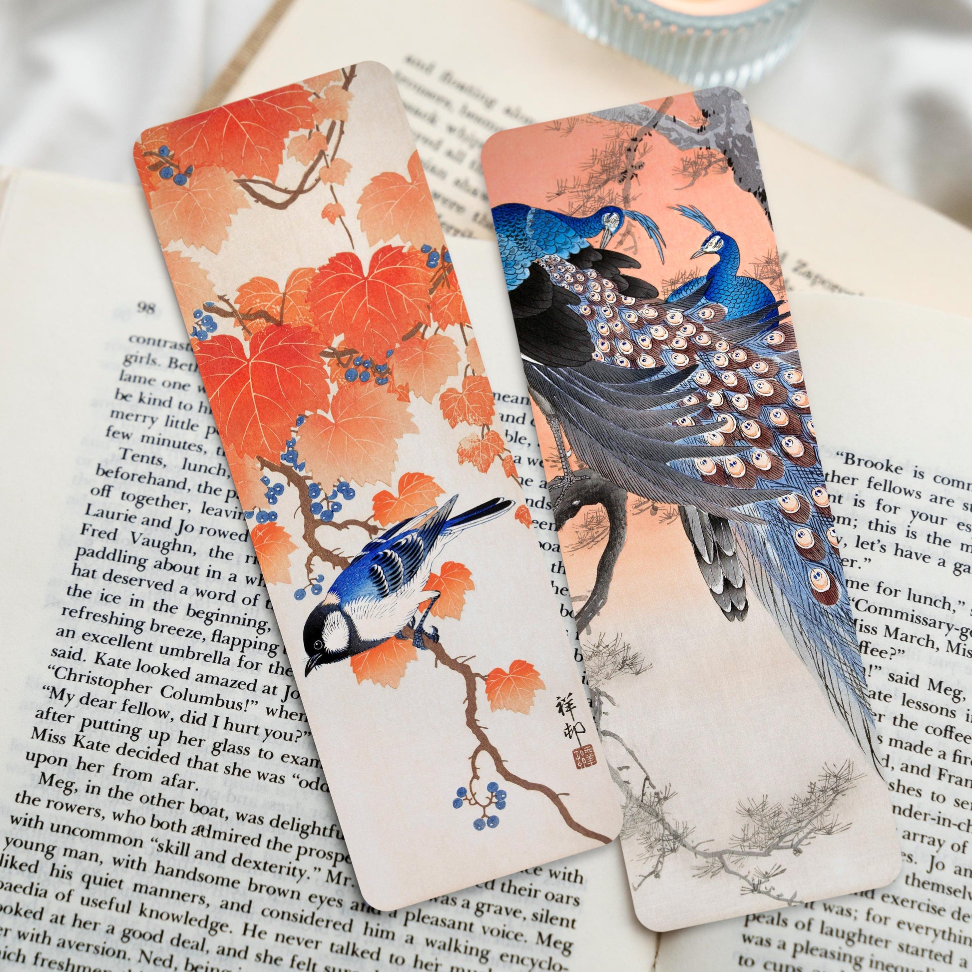 Two bookmarks, one with a blue coloured great tit perched on a branch of a maple leaf tree, and the other with two blue peacocks